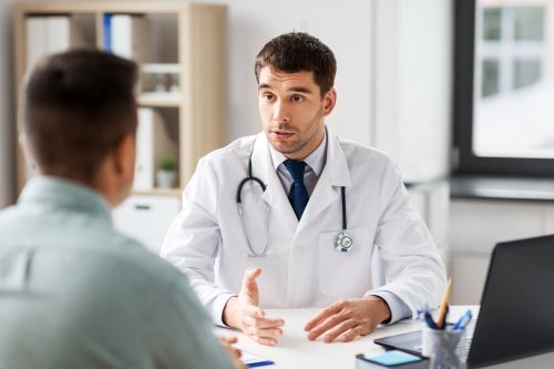 doctor with laptop and male patient at hospital